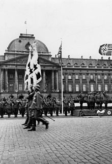 https://upload.wikimedia.org/wikipedia/commons/thumb/3/36/Bundesarchiv_Bild_146-1976-134-27%2C_Belgien%2C_Br%C3%BCssel%2C_Parade_vor_dem_Schloss.jpg/220px-Bundesarchiv_Bild_146-1976-134-27%2C_Belgien%2C_Br%C3%BCssel%2C_Parade_vor_dem_Schloss.jpg